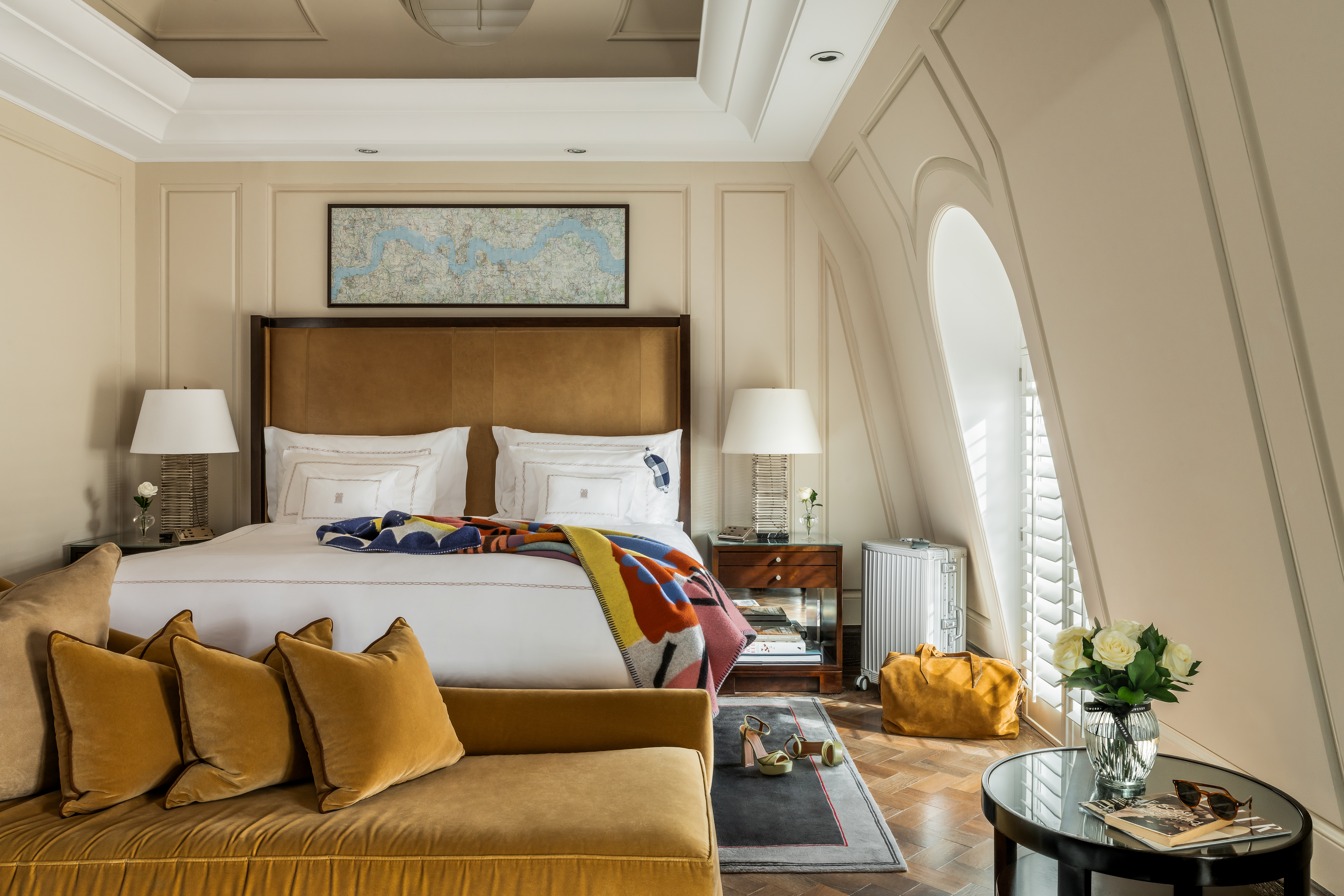 Whitehall Penthouse suite bedroom at Corinthia London luxury hotel with Begg x Co blanket luggage and green heels on floor after night out