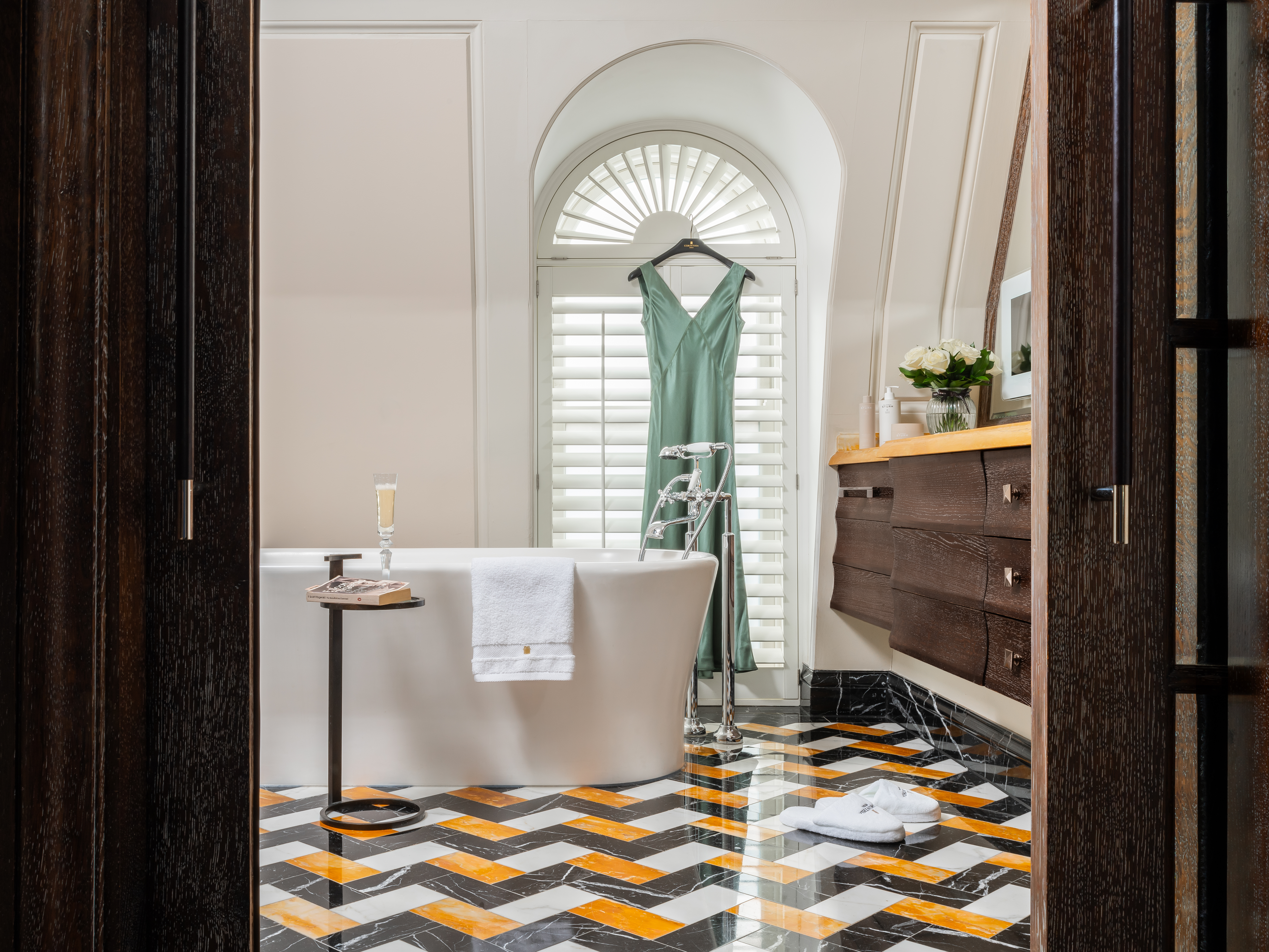 Dress hanging in Whitehall Penthouse suite bathroom at Corinthia London luxury hotel featuring large marble tub