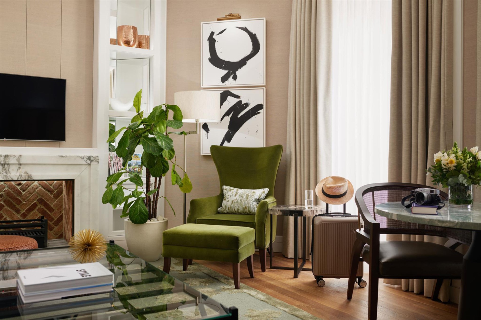 Green chair with footstool, large plant, dining area and fireplace