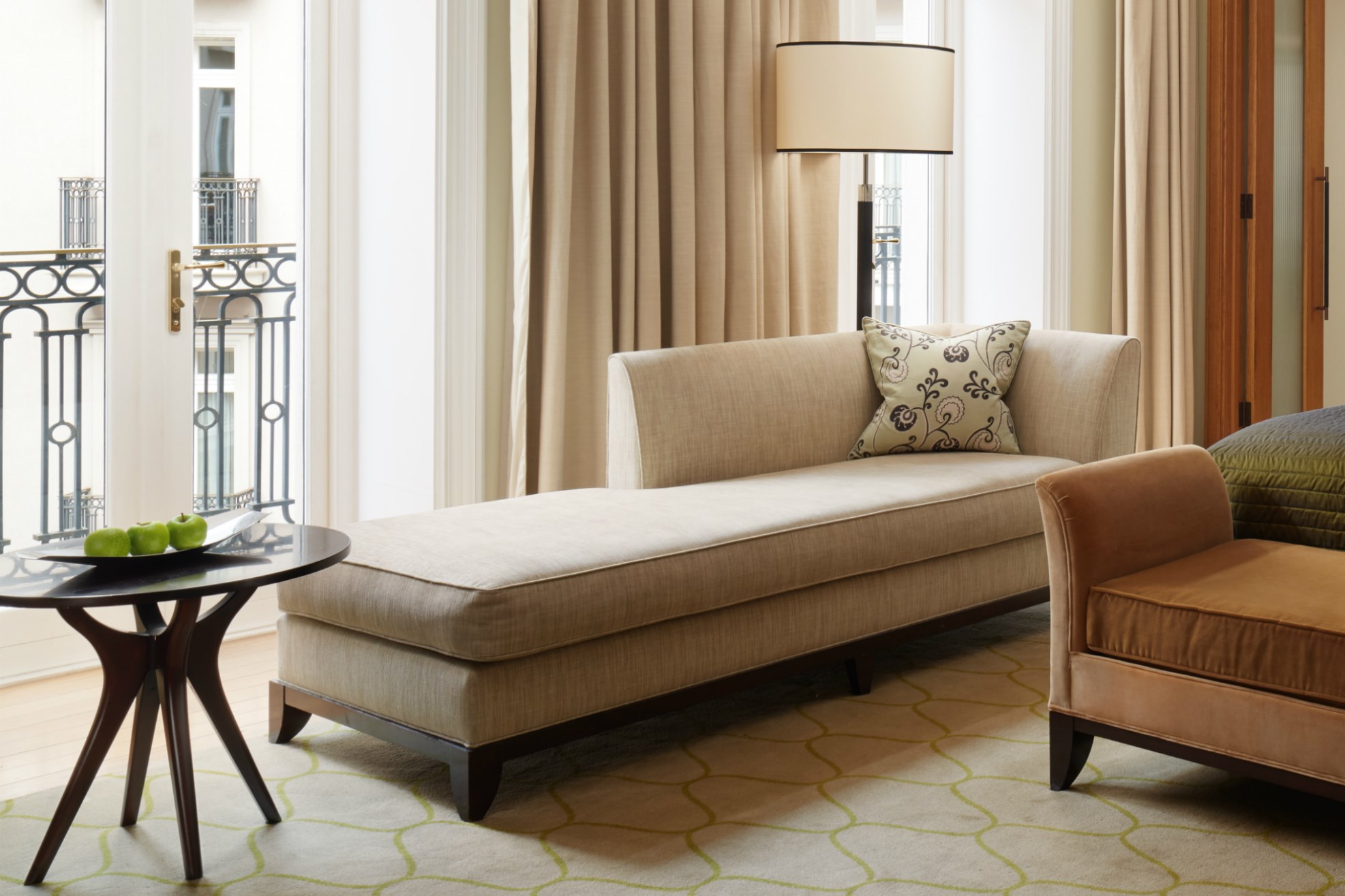 Long white lounger next to side table and large windows