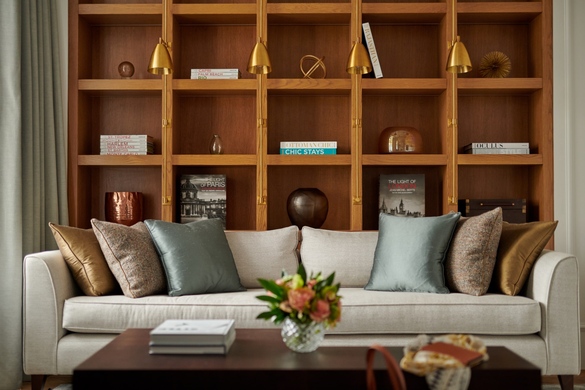 White sofa with colourful cushions in front of wooden shelving