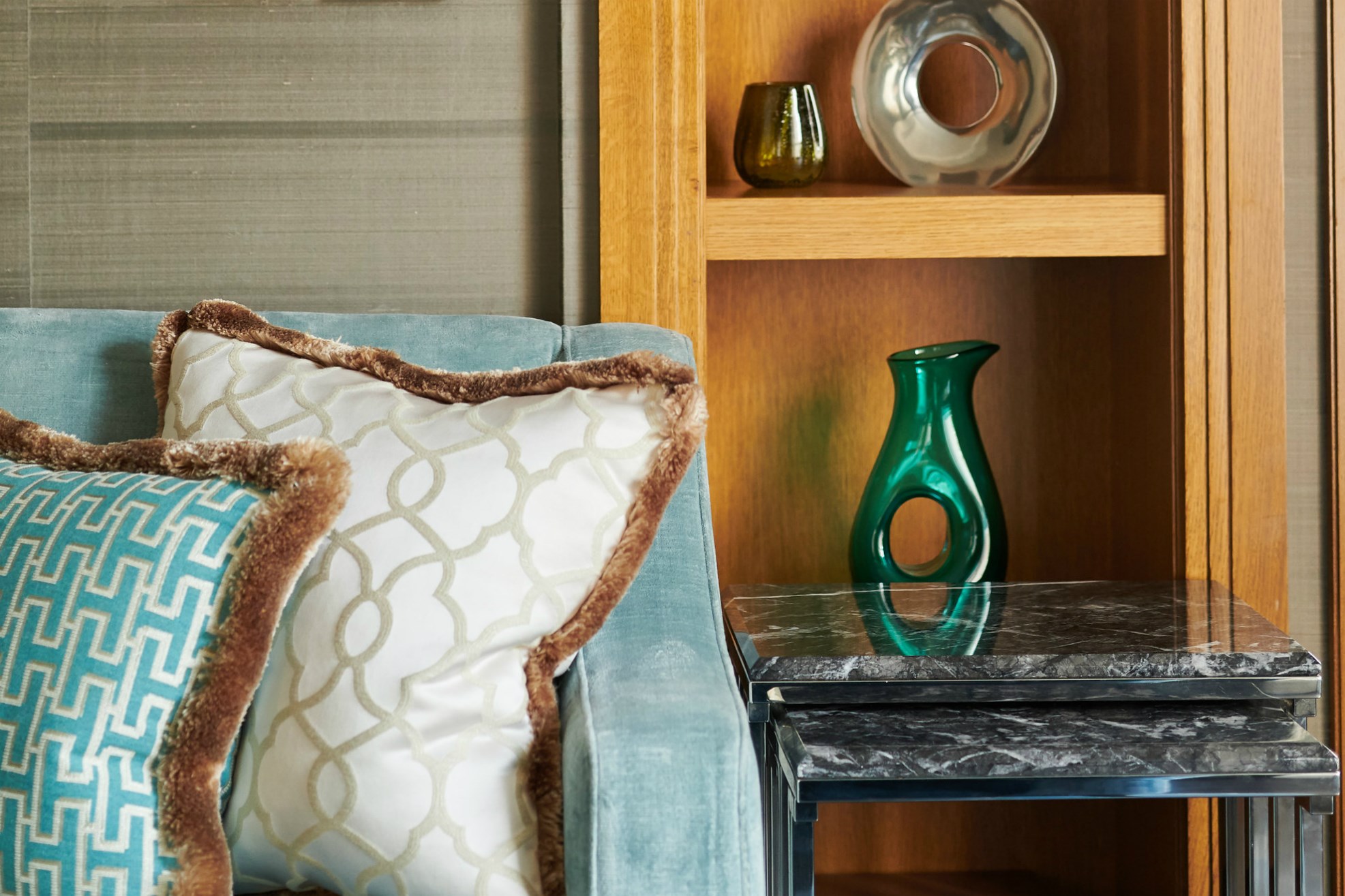 Blue sofa with colourful cushions next to table within Luxury Suite at Corinthia London Hotel.
