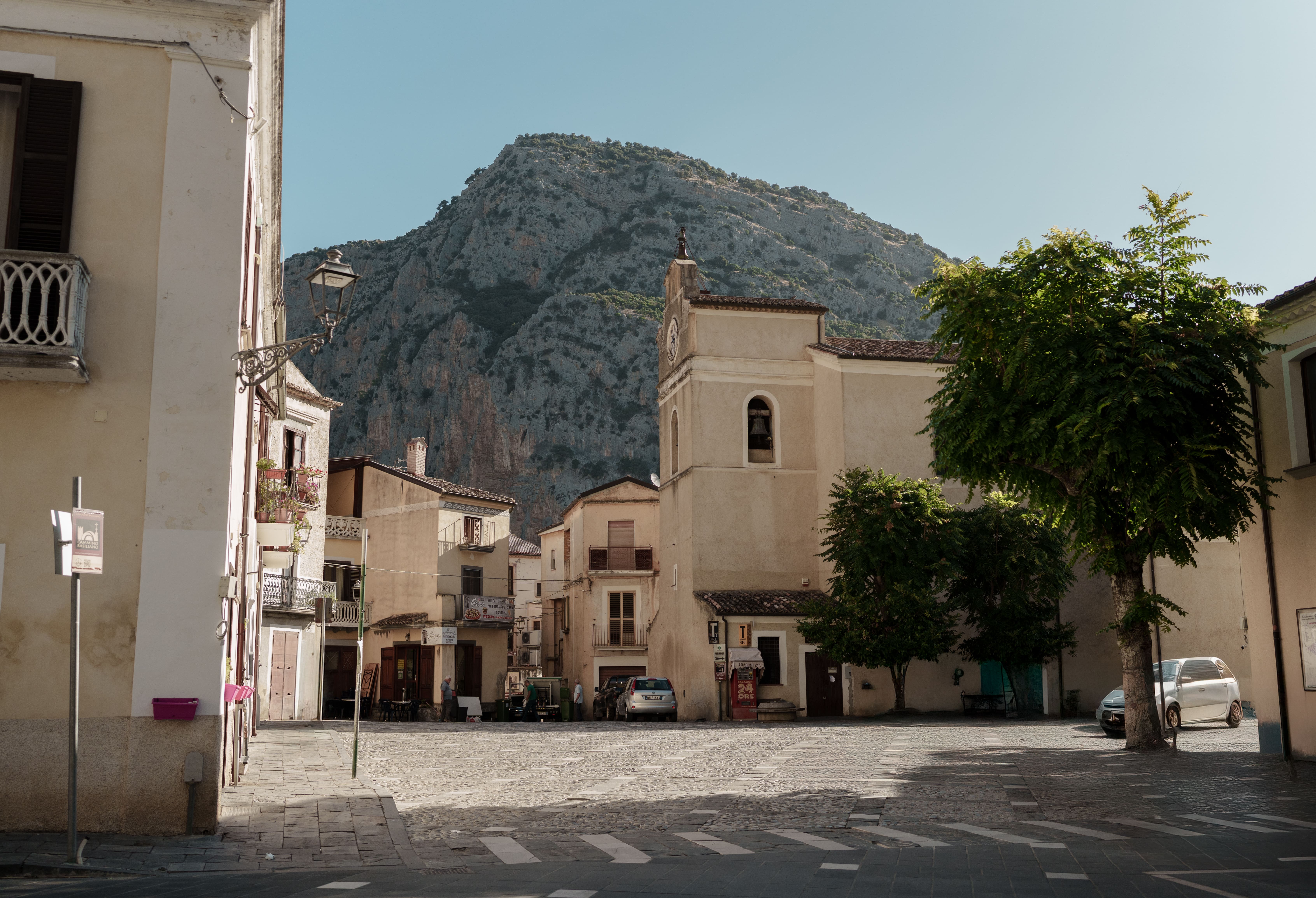 Sunlit Italian village square at the foot of a mountain, evoking the Southern Italian landscapes that inspire Mezzogiorno at Corinthia London