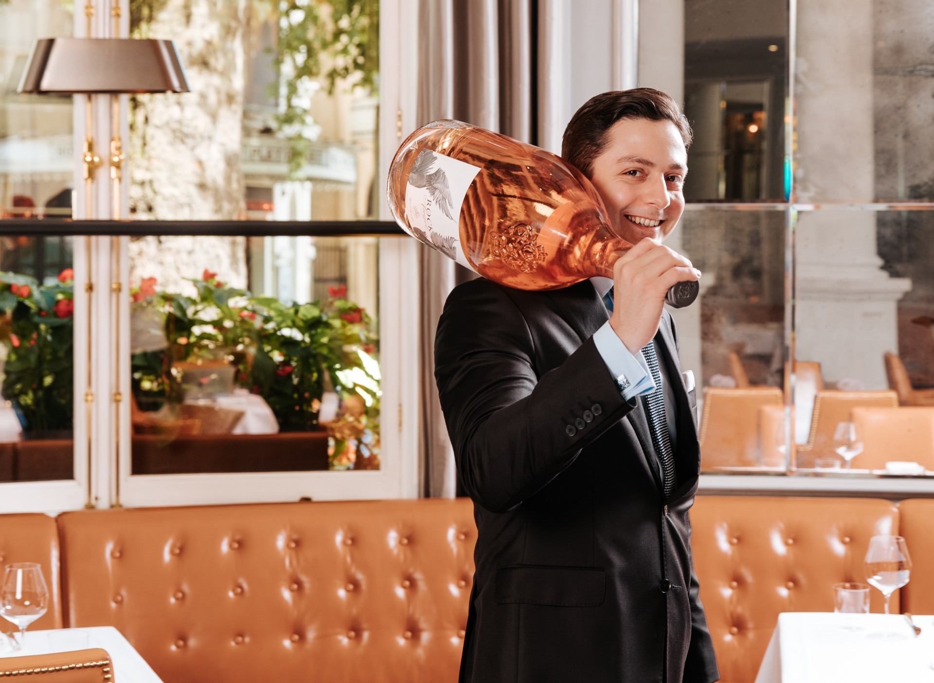Man holding large bottle of wine over his shoulder