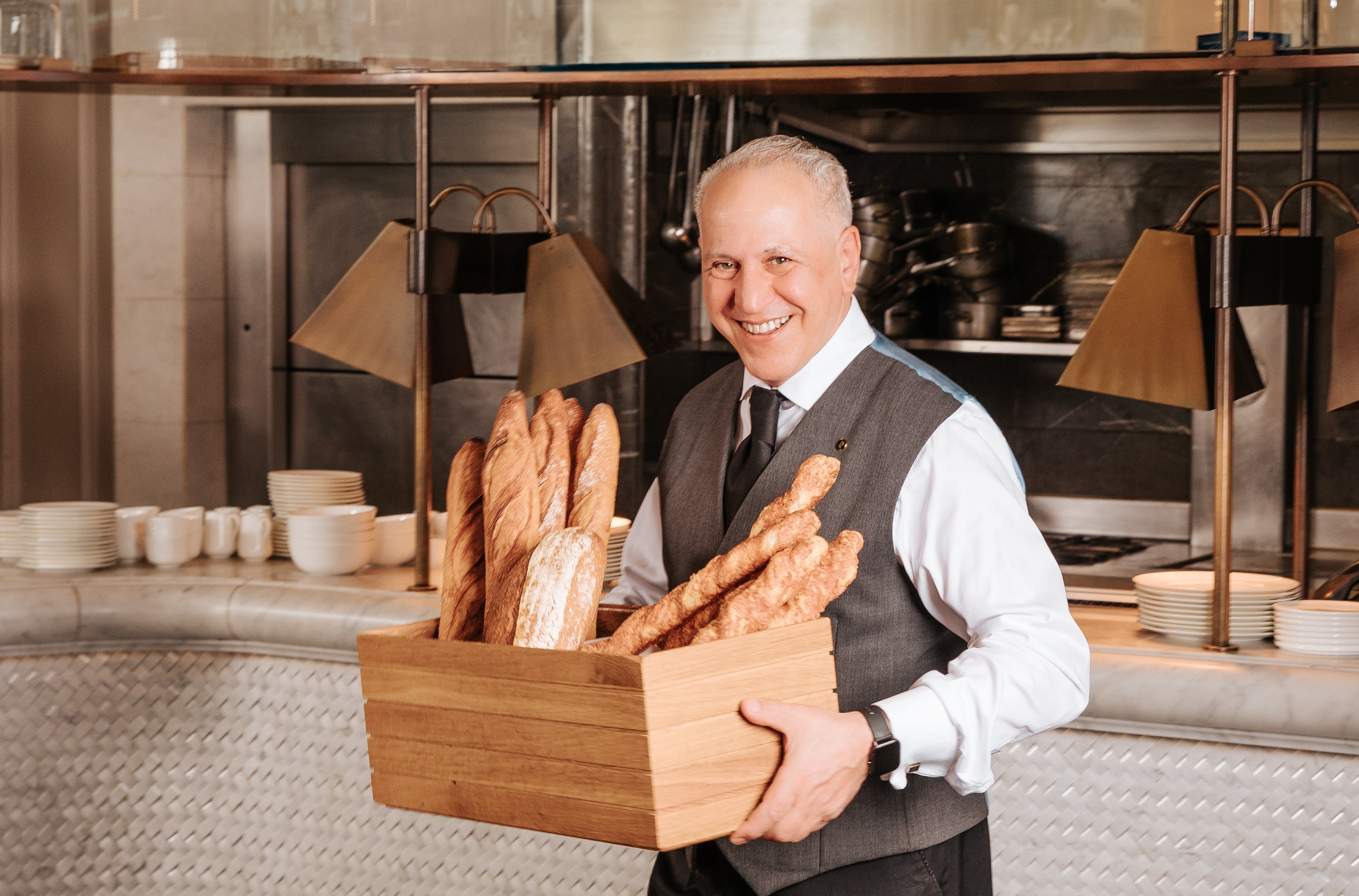 Man holding a wooden box of baguettes