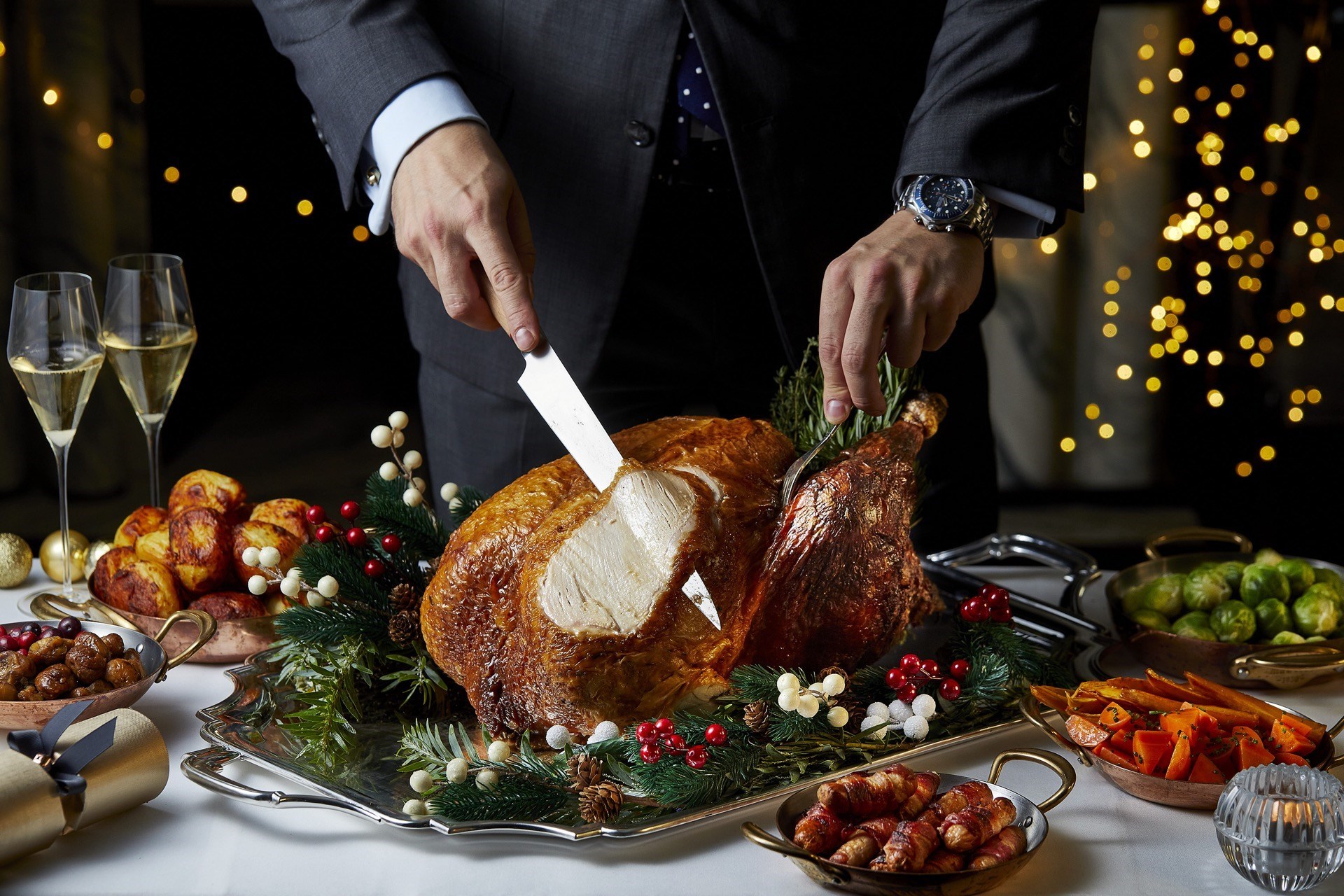 Cutting a festive turkey with all the trimmings and glasses of Champagne