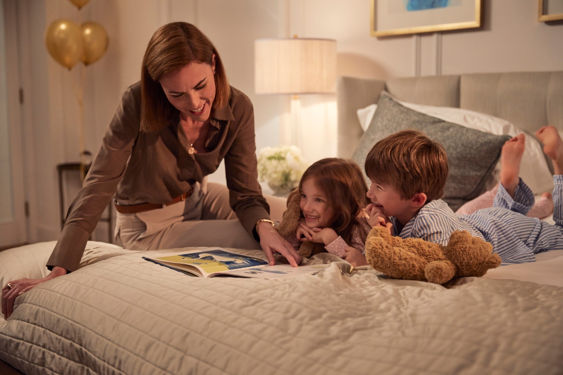 Mum reading bedtime story to girl and boy in bed
