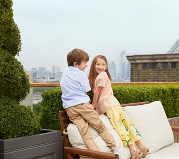 Two kids on a terrace with views of London skyline
