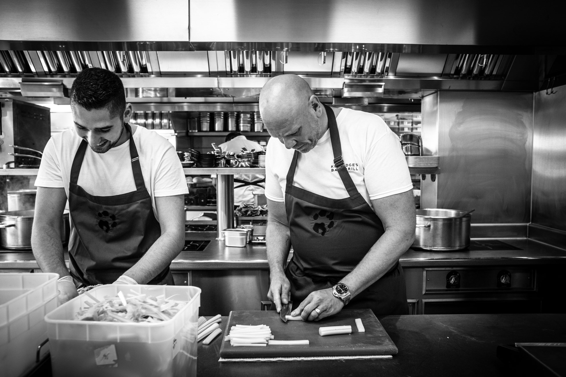 Chef Tom Kerridge and chef cooking in the kitchen in black and white