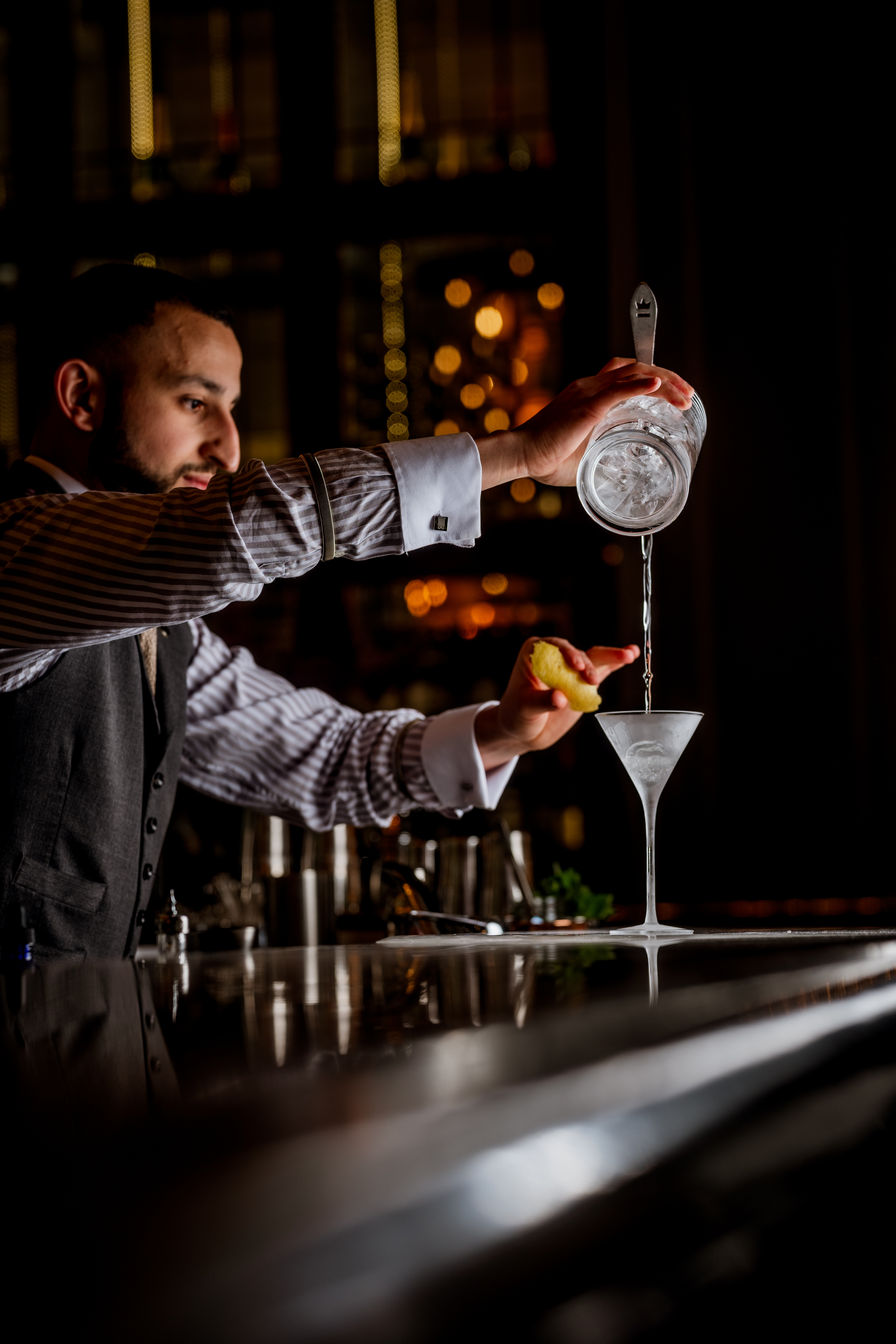 Bartender expertly serving a chilled martini cocktail at The Northall Bar, highlighting elegant mixology in a sophisticated setting
