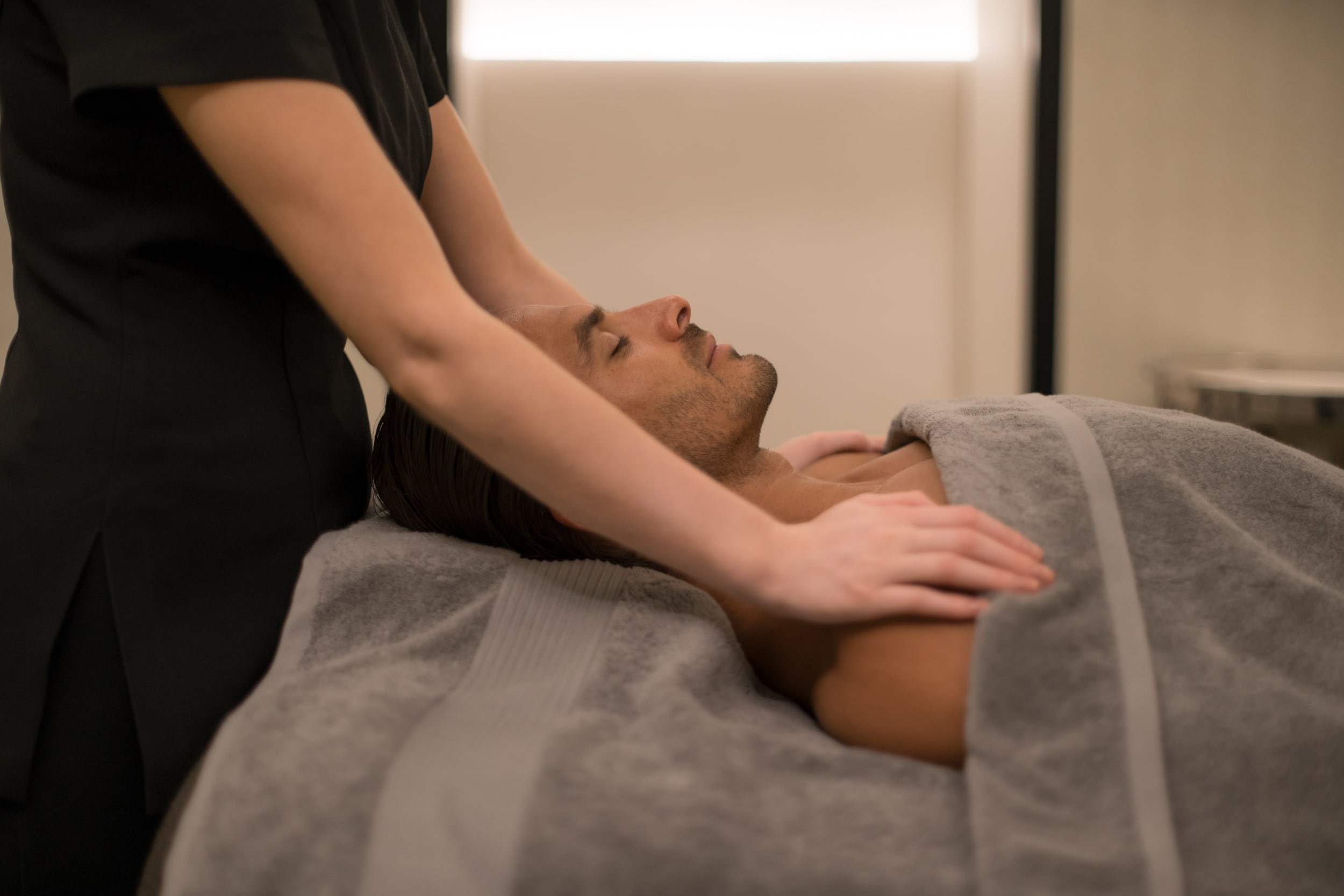 Therapist putting hands on man's shoulders lying down