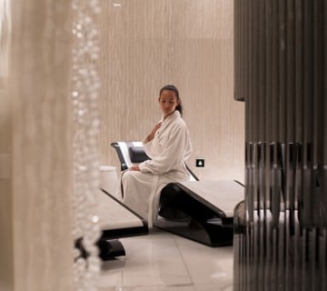 Woman in bathrobe sitting on marble lounger